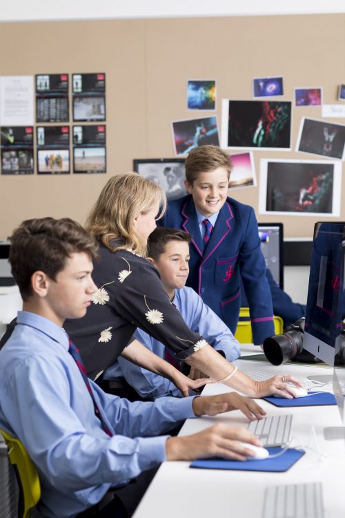 boys learning in classroom with teacher at computer